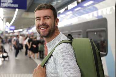 Tren istasyonunda sırt çantalı yakışıklı bir gencin yakın plan portresi.
