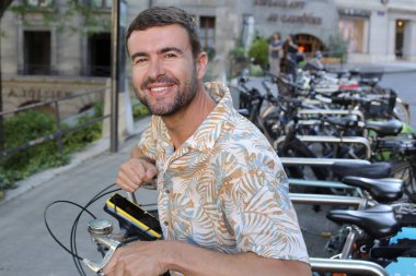 Şehir caddesinde bisiklet parkındaki yakışıklı genç adamın yakın plan portresi.