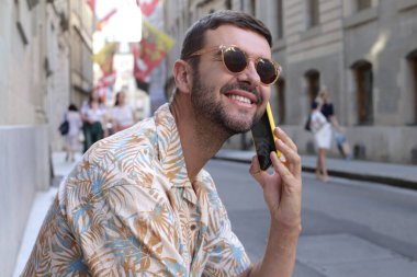 close-up portrait of handsome young man talking by phone on street