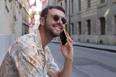 close-up portrait of handsome young man talking by phone on street