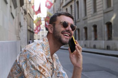close-up portrait of handsome young man talking by phone on street