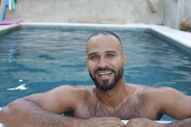 Yüzme havuzunda rahatlayan yakışıklı genç adamın yakın plan portresi.