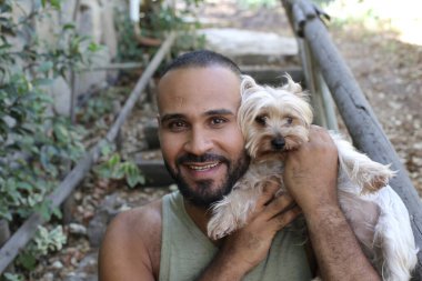 Parkta sevimli köpek yavrusu tutan yakışıklı genç adamın yakın plan portresi.