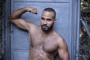 Gri duvardaki yakışıklı üstsüz genç adamın yakın plan portresi.