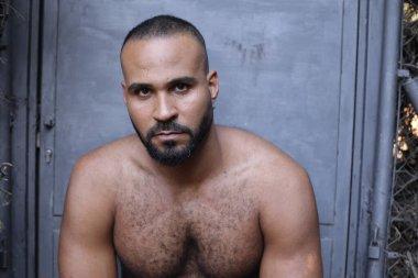 Gri duvardaki yakışıklı üstsüz genç adamın yakın plan portresi.