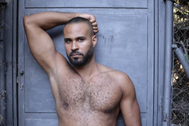 Gri duvardaki yakışıklı üstsüz genç adamın yakın plan portresi.