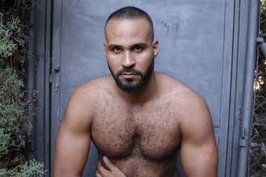 Gri duvardaki yakışıklı üstsüz genç adamın yakın plan portresi.