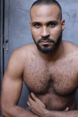Gri duvardaki yakışıklı üstsüz genç adamın yakın plan portresi.