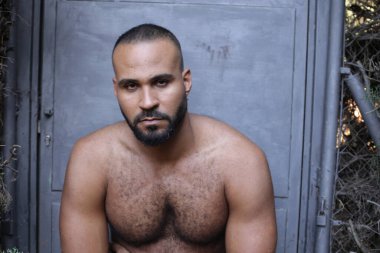 Gri duvardaki yakışıklı üstsüz genç adamın yakın plan portresi.