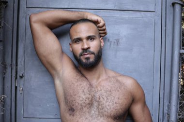 Gri duvardaki yakışıklı üstsüz genç adamın yakın plan portresi.