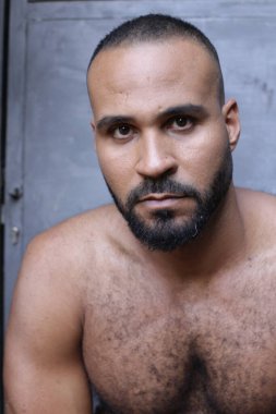 Gri duvardaki yakışıklı üstsüz genç adamın yakın plan portresi.
