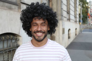 close-up portrait of handsome young curly man sitting on city street