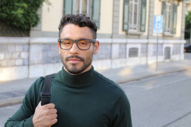 close-up portrait of handsome young man in turtleneck sweater on city street