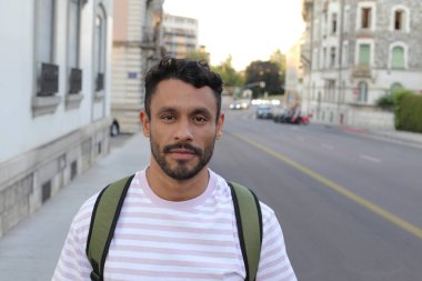 close-up portrait of handsome young man in t-shirt with backpack on city street