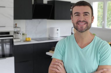 Mutfakta kolları çapraz duran yakışıklı bir gencin portresi.