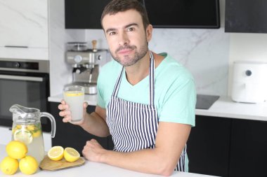 Evde bir bardak limonata tutan yakışıklı bir gencin portresi.