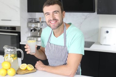 Evde bir bardak limonata tutan yakışıklı bir gencin portresi.