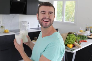 Mutfakta elinde bir bardak süt tutan yakışıklı genç adamın portresi.
