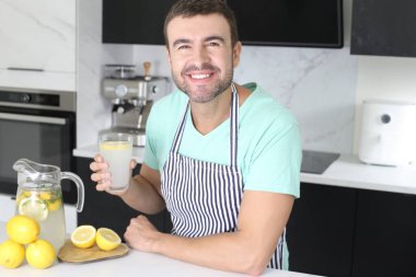 Evde bir bardak limonata tutan yakışıklı bir gencin portresi.