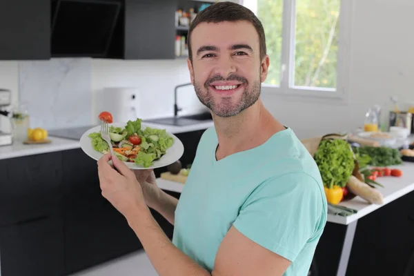 キッチンでサラダを持っているハンサムな若い男の肖像画 — ストック写真