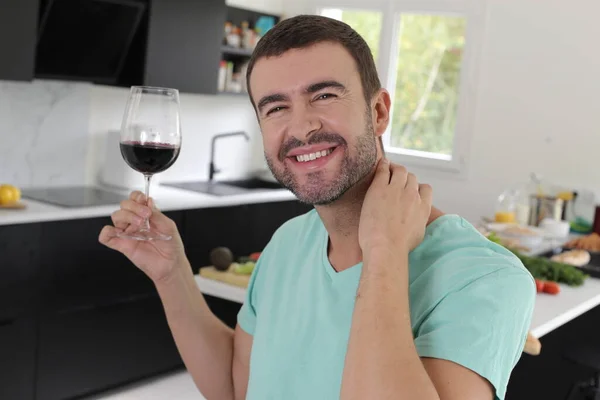 キッチンで赤ワインを持っているハンサムな若い男の肖像画 — ストック写真