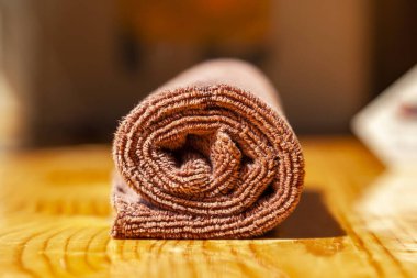 Kahverengi üç katlı mikrofiber çay havlusu ahşap bir yüzeye sarılmış.