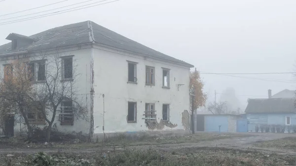 Закинутий двоповерховий дерев'яний будинок біля дороги в туманний день — стокове фото