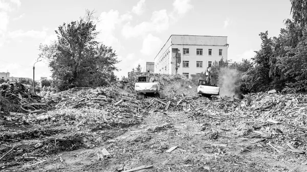 A kotrók lerombolják az épületet. Építőipari bontás, fekete-fehér fotó — Stock Fotó