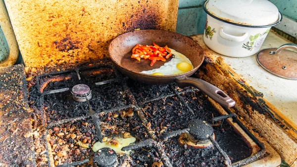 汚れたストーブとそれに壊れた鶏の卵,揚げ卵と甘いコショウでフライパン ロイヤリティフリーのストック写真