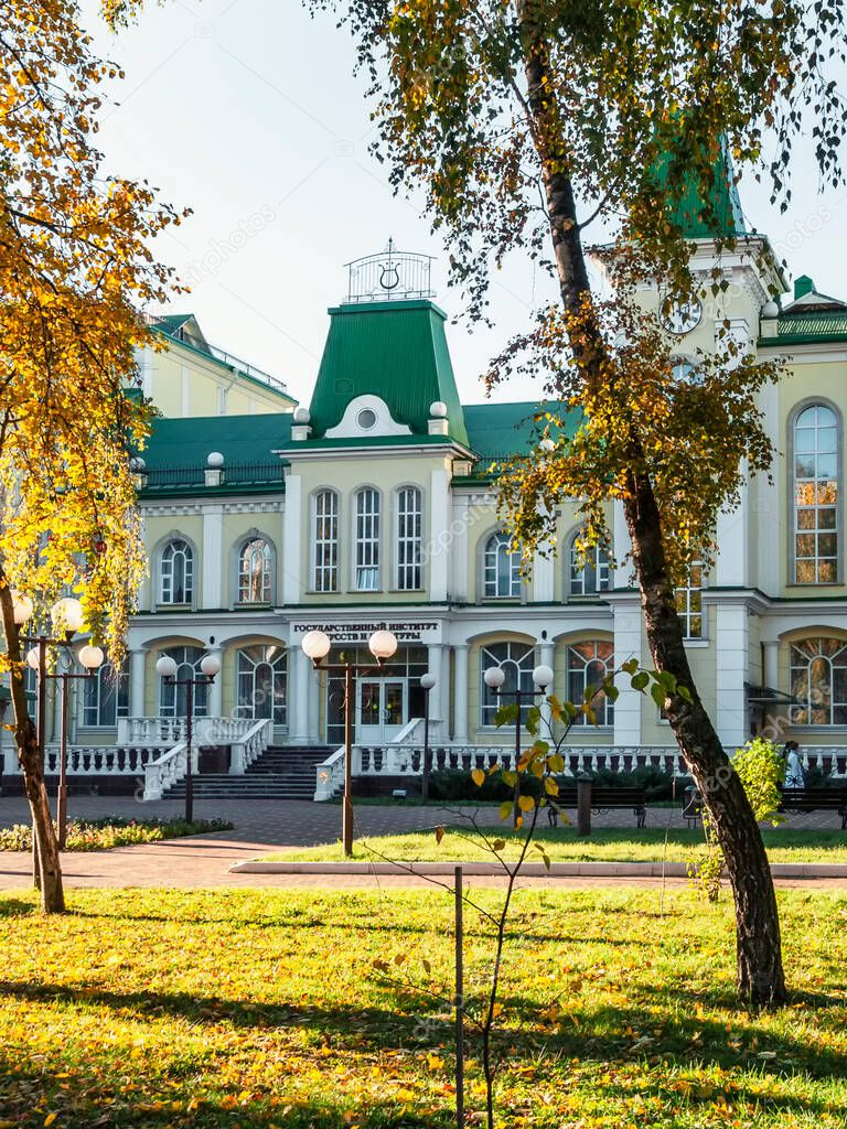 The facade of the building of the Oryol State Institute of Culture, birch trees and the lawn in front of the entrance.