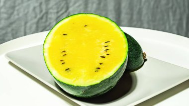 Ejderhaların küçük, taze, parlak karpuzu. Beyaz ve gri arka planda yumurta sarısı.