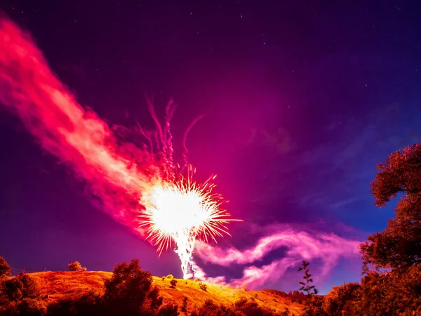 Fényes piros tűzijáték egy dombon egy természetes táj éjjel szemben a csillagos ég, a vidéki nyaralás táj — Stock Fotó