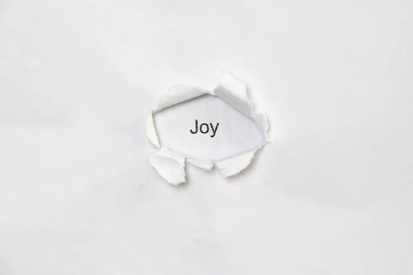 Word joy on white isolated background through the wound hole in the paper. — Fotografia de Stock