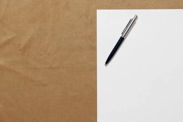Πρότυπο του λευκού χαρτιού με στυλό βρίσκεται σε ανοιχτό καφέ ύφασμα φόντο. Έννοια του επιχειρηματικού σχεδίου και της στρατηγικής. Στοκ φωτογραφία με κενό χώρο για κείμενο και σχεδιασμό — Φωτογραφία Αρχείου
