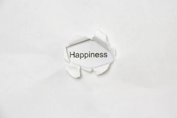Слово щастя на білому ізольованому тлі через отвір рани в папері . — стокове фото