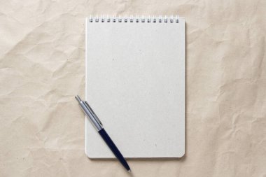  Beyaz sarmalanmış yay ve arkaplandaki bej buruşuk el işi kağıdının üzerindeki kalemle gri not defteri.