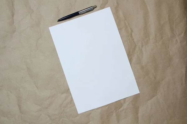 Feuille blanche vide de format A4 avec stylo sur un papier artisanal beige. — Photo