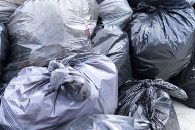 Çöp sahasında büyük siyah torbalarda bir çöp yığını. İşlem için atık hazırlandı