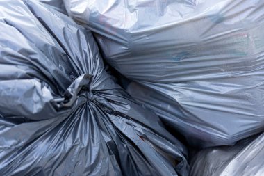 Çöp sahasında büyük siyah torbalarda bir çöp yığını. İşlem için atık hazırlandı