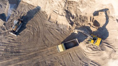 Kazıcı, minerallerin çıkarılması için toprak hareketinde çalışıyor. Kazıcı taş ocağında kum ve çakıl kazıyor. İnşaat alanında toprak çalışması sırasında ağır inşaat makineleri.