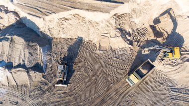 Kazıcı, minerallerin çıkarılması için toprak hareketinde çalışıyor. Kazıcı taş ocağında kum ve çakıl kazıyor. İnşaat alanında toprak çalışması sırasında ağır inşaat makineleri.