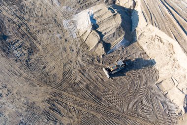 Kazıcı, minerallerin çıkarılması için toprak hareketinde çalışıyor. Kazıcı taş ocağında kum ve çakıl kazıyor. İnşaat alanında toprak çalışması sırasında ağır inşaat makineleri.