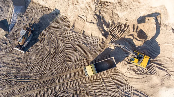 Kazıcı, minerallerin çıkarılması için toprak hareketinde çalışıyor. Kazıcı taş ocağında kum ve çakıl kazıyor. İnşaat alanında toprak çalışması sırasında ağır inşaat makineleri.