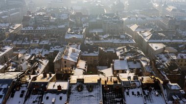 Kışın eski bir kasaba, güneş doğarken insanlar olmadan. Lviv şehrinin tarihi merkezi. Çatılar karla kaplı. İnsansız hava aracı, kışın, güneş doğarken, insansız eski bir kasabanın fotoğrafını çeker. Lviv şehrinin tarihi merkezi. Çatılar karla kaplı. D