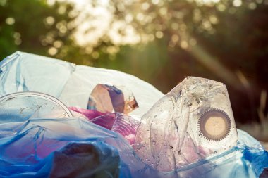 Dünyanın çevresel sorununda plastik kirliliği. Beyaz eldivenli bir el, çöpü plastik bir torbaya koyar. Kirlenmiş bölgelerdeki çöplerin çıkarılması ve temizlenmesi