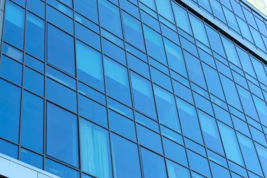 Modern office building facade. Tall business center with a glass facade. Construction of a glass facade structure. The glare of the sun on the glass wall of a skyscraper