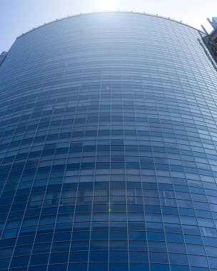Modern office building facade. Tall business center with a glass facade. Construction of a glass facade structure. The glare of the sun on the glass wall of a skyscraper