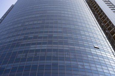 Modern office building facade. Tall business center with a glass facade. Construction of a glass facade structure. The glare of the sun on the glass wall of a skyscraper