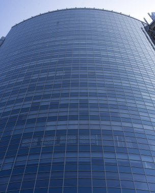 Modern office building facade. Tall business center with a glass facade. Construction of a glass facade structure. The glare of the sun on the glass wall of a skyscraper