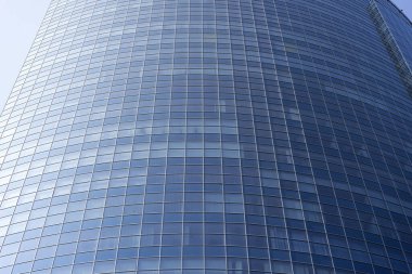 Modern office building facade. Tall business center with a glass facade. Construction of a glass facade structure. The glare of the sun on the glass wall of a skyscraper